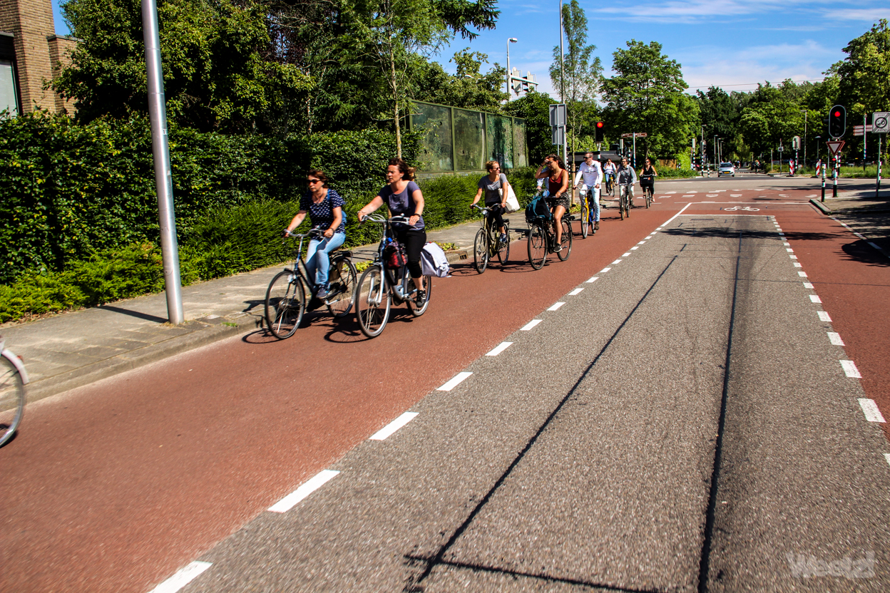 Breite, eingefärbte Radfahrstreifen auf beiden Seiten sind für Radfahrende. Autos nutzen den Mittelstreifen, wenn sie Radfahrende überholen., Breite, eingefärbte Radfahrstreifen auf beiden Seiten sind für Radfahrende. Autos nutzen den Mittelstreifen, wenn sie Radfahrende überholen.,